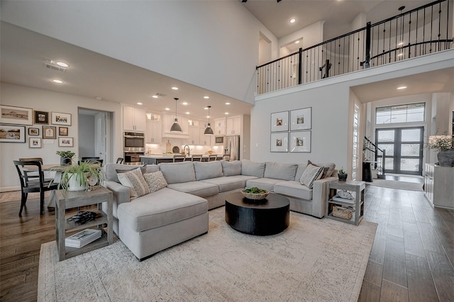 living room with recessed lighting, visible vents, a towering ceiling, and wood finished floors