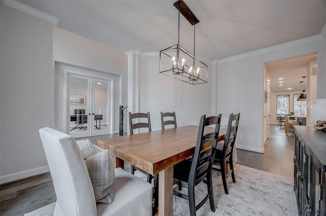 dining area with wood finished floors, baseboards, french doors, ornamental molding, and decorative columns