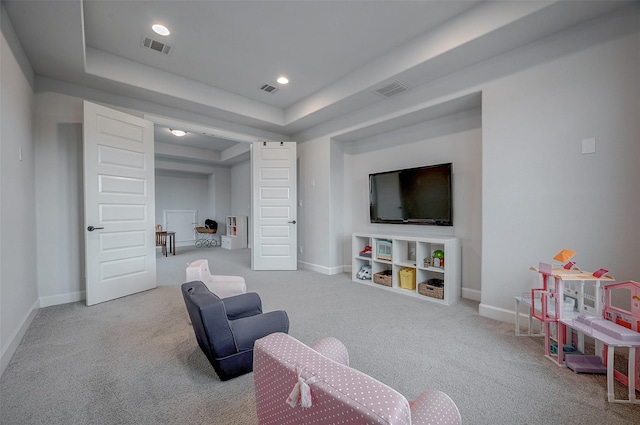 living room featuring a tray ceiling, visible vents, and baseboards