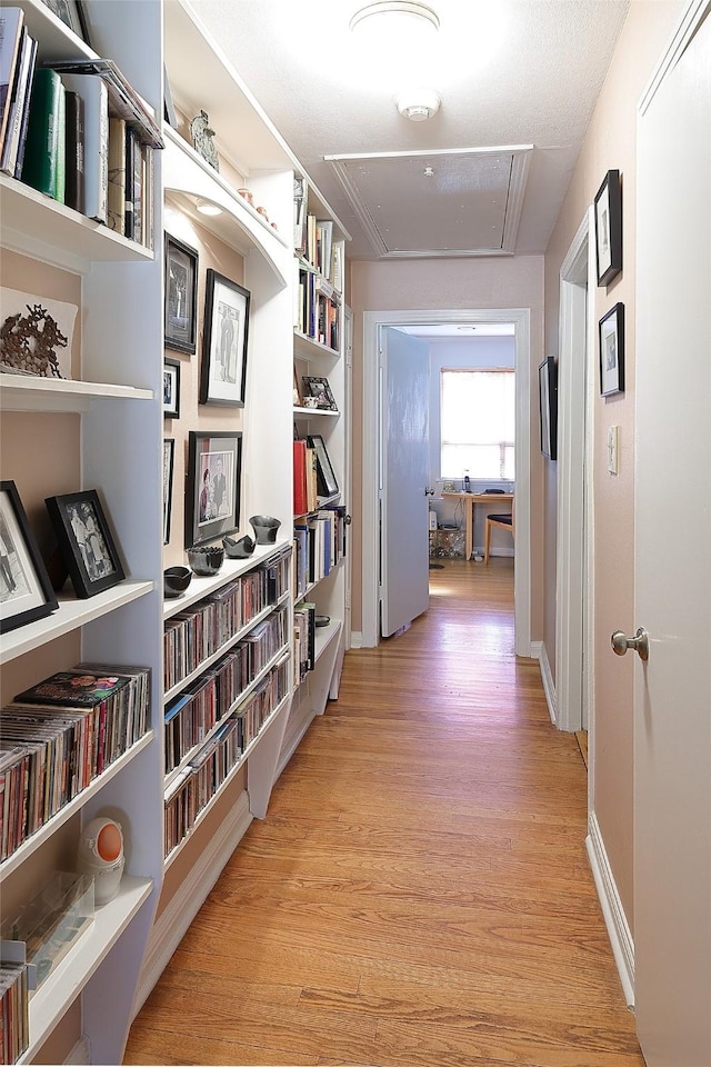 corridor with attic access, baseboards, and light wood-style flooring