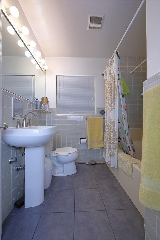 full bath featuring visible vents, toilet, tile patterned floors, shower / bath combo with shower curtain, and tile walls