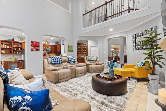 living room featuring arched walkways, tile patterned floors, a high ceiling, and baseboards