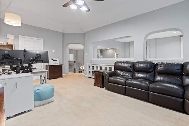 carpeted living area with ceiling fan, arched walkways, and vaulted ceiling