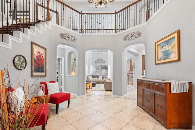 interior space featuring arched walkways, light tile patterned flooring, a notable chandelier, a high ceiling, and stairway