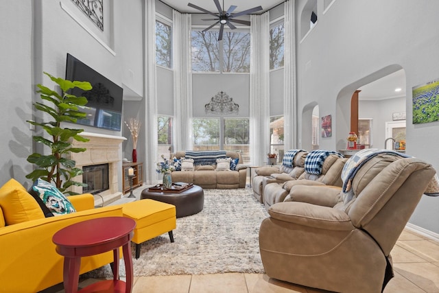 living room with arched walkways, a glass covered fireplace, a high ceiling, and tile patterned flooring