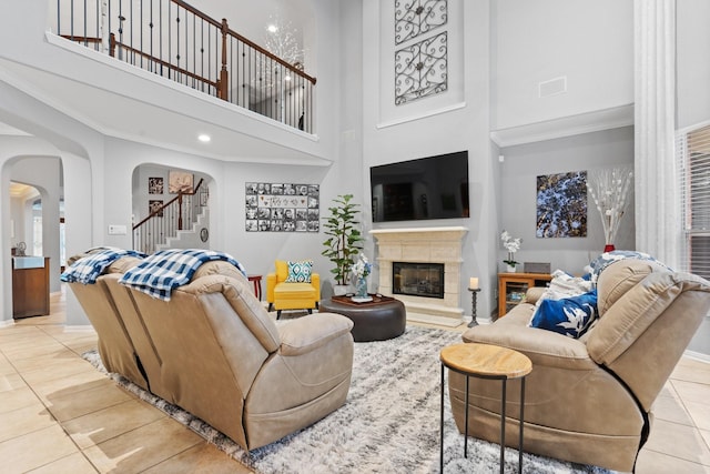 living room with stairway, a towering ceiling, tile patterned floors, arched walkways, and baseboards