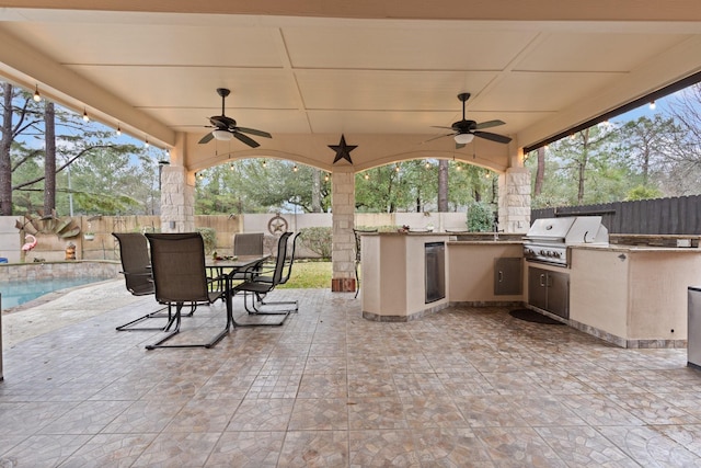 view of patio with a fenced backyard, a grill, a ceiling fan, and exterior kitchen