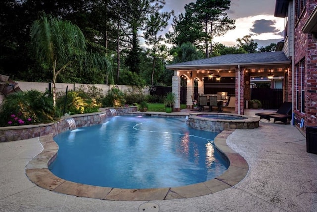 pool at dusk with a fenced backyard, a patio, and a pool with connected hot tub