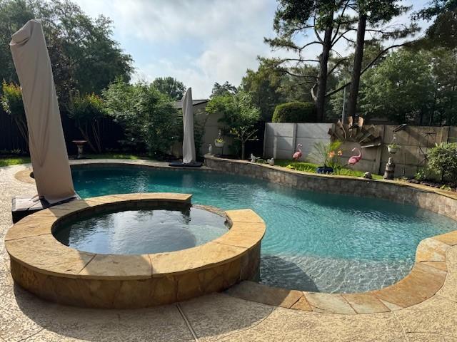 view of pool with a pool with connected hot tub and a fenced backyard