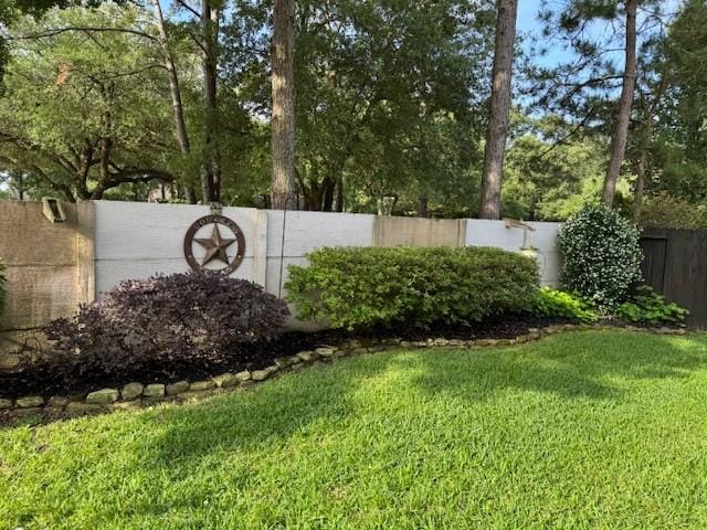 community / neighborhood sign with a yard and fence