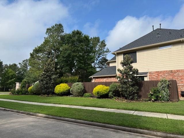 view of side of property featuring brick siding and fence