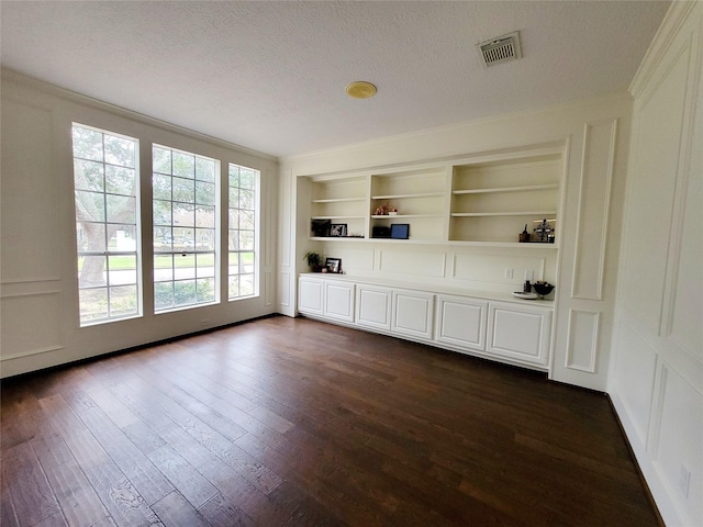 interior space with built in shelves, dark hardwood / wood-style flooring, a textured ceiling, and crown molding