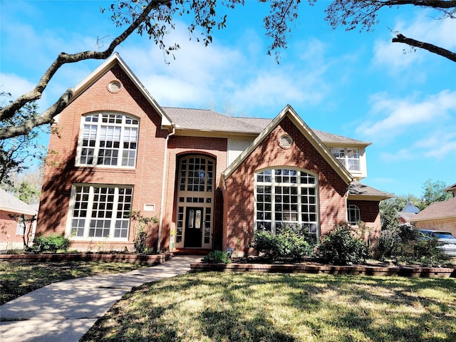 traditional-style home with a front lawn and brick siding