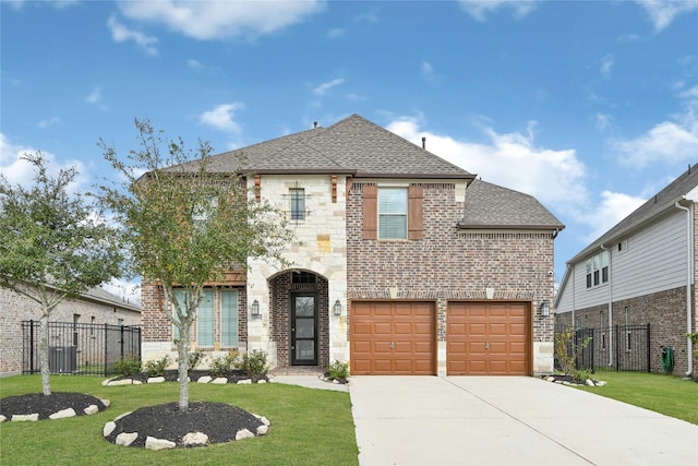 view of front of home featuring a shingled roof, a front lawn, fence, stone siding, and driveway