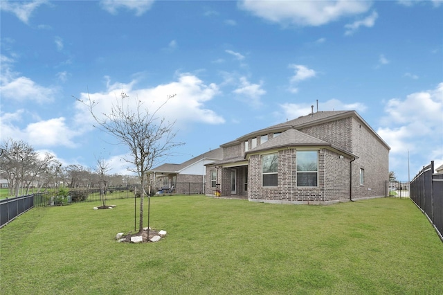 back of house with a yard, a fenced backyard, and brick siding