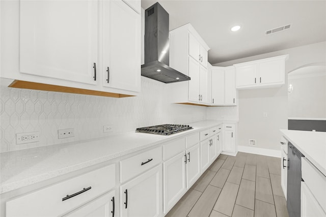 kitchen with wall chimney range hood, visible vents, backsplash, and stainless steel appliances