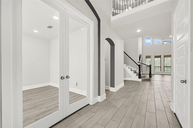 foyer featuring stairway, baseboards, a towering ceiling, and wood tiled floor