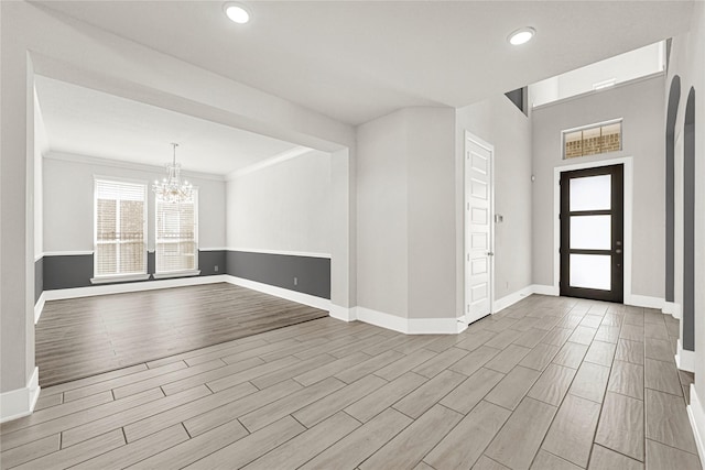 foyer with wood finish floors, baseboards, and an inviting chandelier