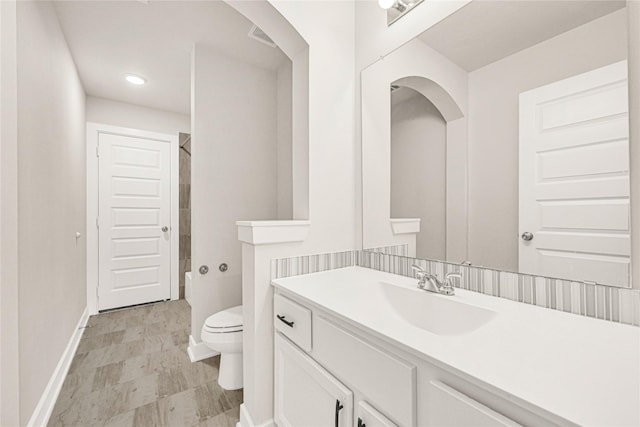 full bath featuring vanity, toilet, baseboards, and walk in shower