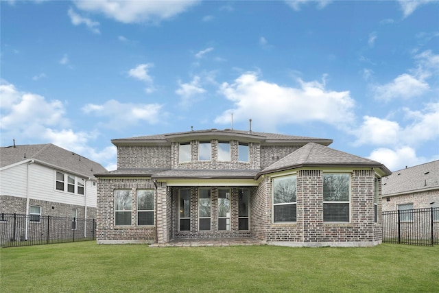 rear view of property featuring a yard, brick siding, and a fenced backyard