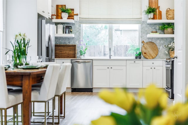 bar featuring stainless steel appliances, white cabinetry, sink, and decorative backsplash