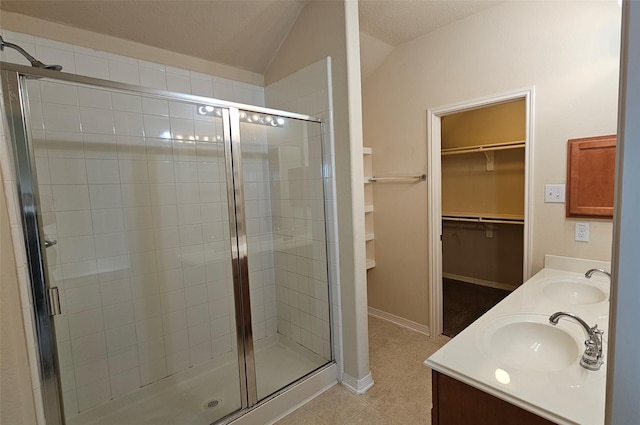 full bathroom with a spacious closet, a sink, and a shower stall