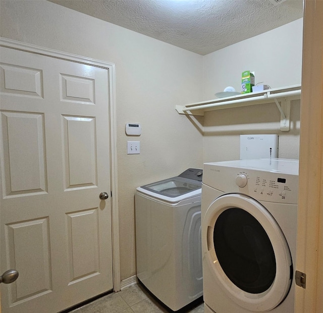 laundry room with laundry area, a textured ceiling, washing machine and clothes dryer, and light tile patterned floors