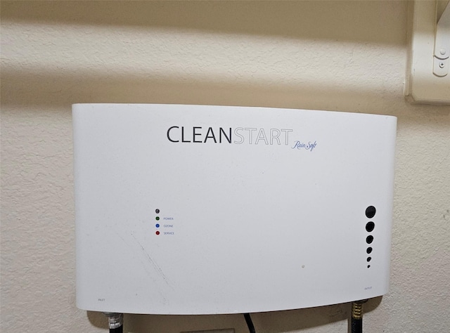 room details featuring water heater and a textured wall