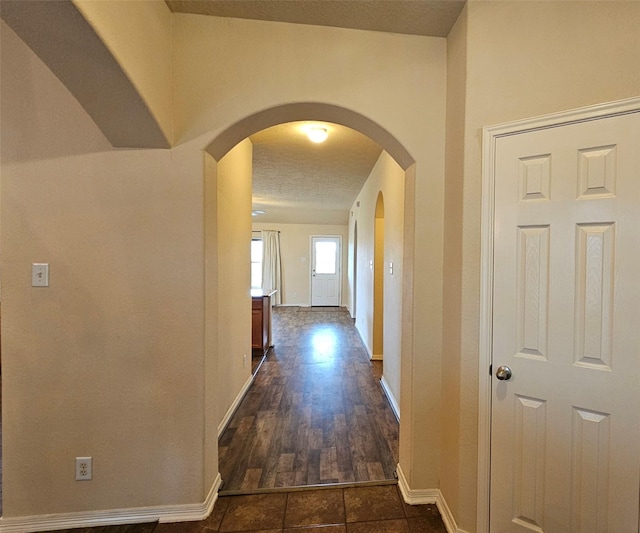 corridor with arched walkways and baseboards