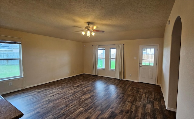 interior space featuring a textured ceiling, baseboards, dark wood finished floors, and a ceiling fan