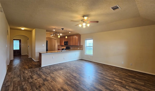 kitchen featuring visible vents, arched walkways, dark wood-style floors, decorative light fixtures, and a peninsula