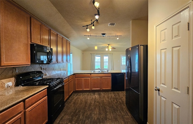 kitchen featuring a peninsula, dark wood-type flooring, a sink, black appliances, and brown cabinetry