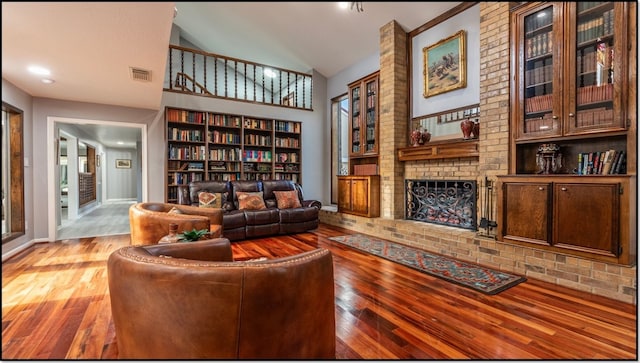 sitting room with built in shelves, high vaulted ceiling, light hardwood / wood-style floors, and a brick fireplace