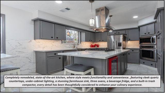 kitchen with wine cooler, gray cabinetry, appliances with stainless steel finishes, a kitchen island, and island exhaust hood