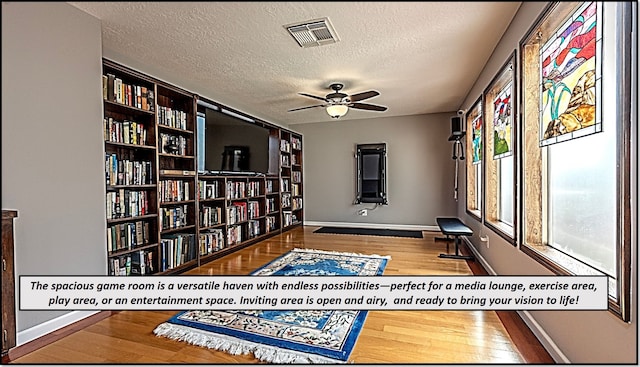 sitting room with ceiling fan, hardwood / wood-style floors, and a textured ceiling