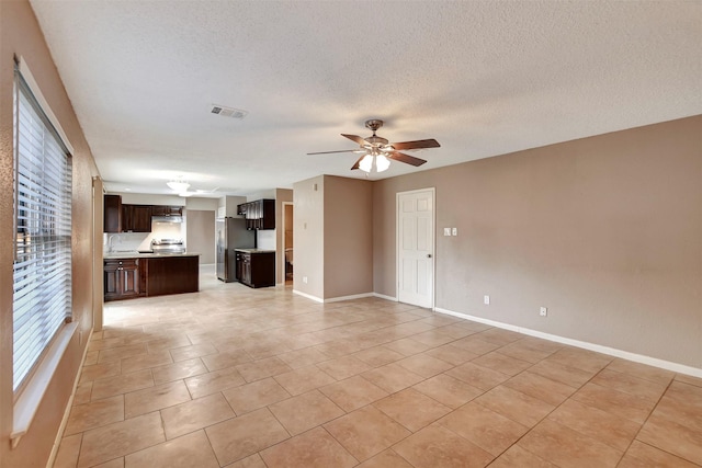 unfurnished living room featuring light tile patterned flooring, ceiling fan, sink, and a textured ceiling