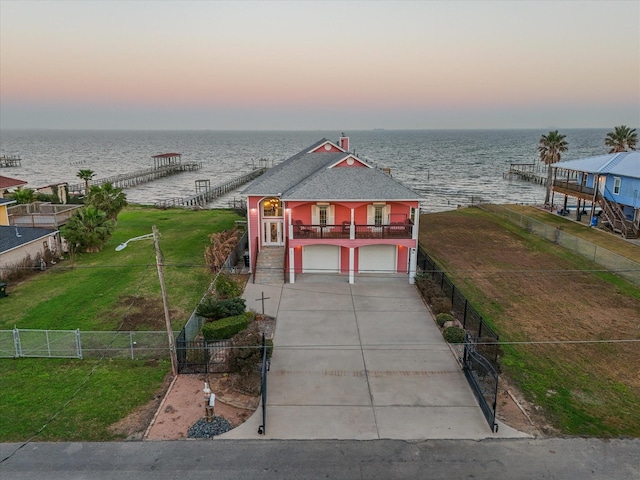 view of front of house featuring a yard, a garage, a balcony, and a water view