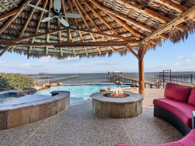 view of pool featuring an infinity pool, a water view, a fire pit, and a gazebo