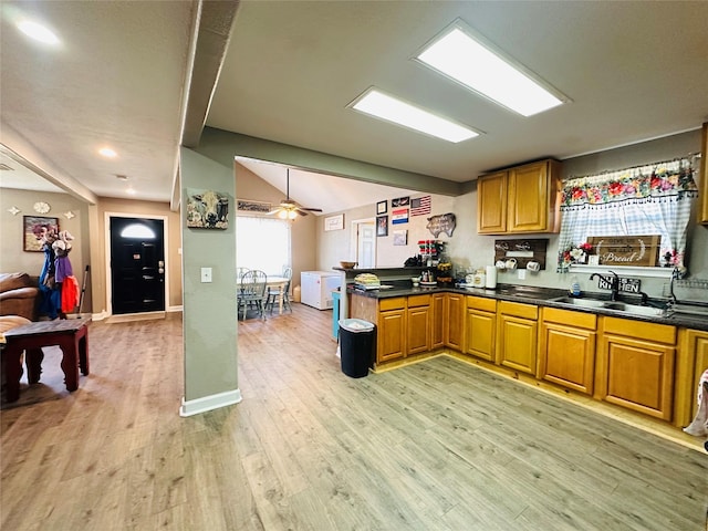 kitchen with lofted ceiling, sink, light hardwood / wood-style flooring, kitchen peninsula, and ceiling fan