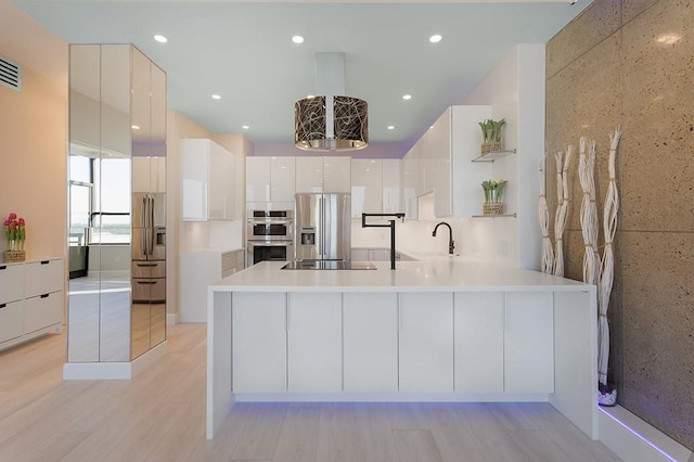 kitchen featuring pendant lighting, sink, appliances with stainless steel finishes, white cabinetry, and light wood-type flooring