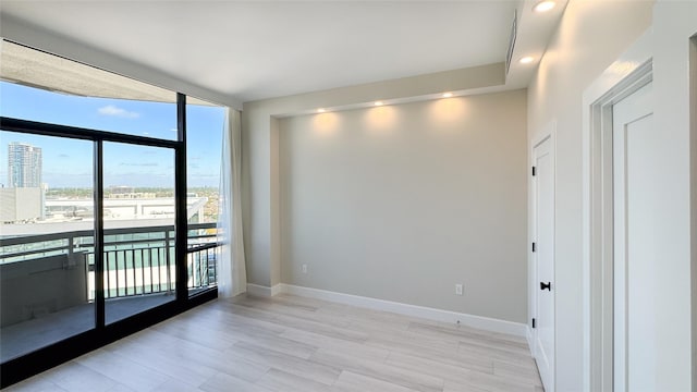 spare room featuring expansive windows and light hardwood / wood-style floors