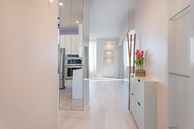 kitchen featuring stainless steel appliances, light hardwood / wood-style flooring, and white cabinets