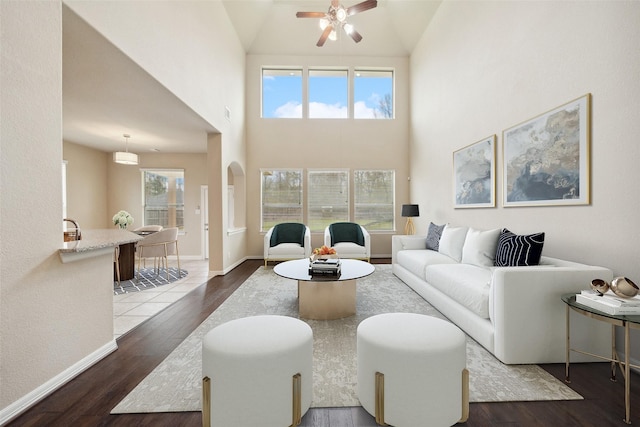 living room with wood finished floors, a ceiling fan, and baseboards