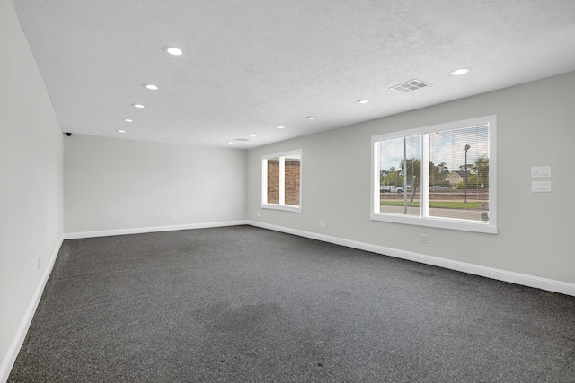 spare room featuring baseboards, visible vents, and a textured ceiling