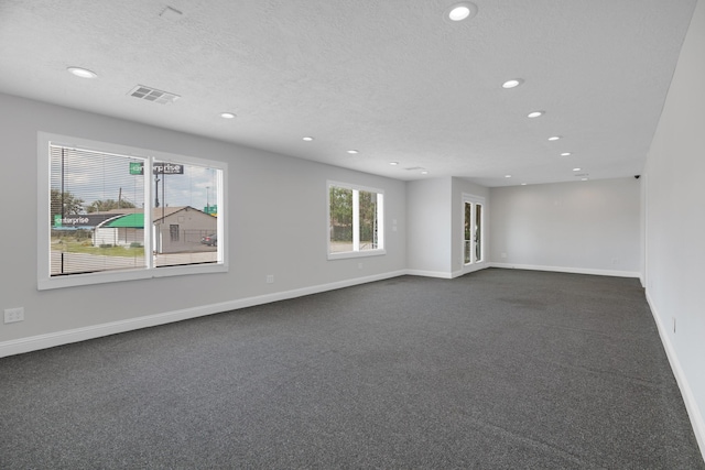 unfurnished room with baseboards, visible vents, dark colored carpet, a textured ceiling, and recessed lighting