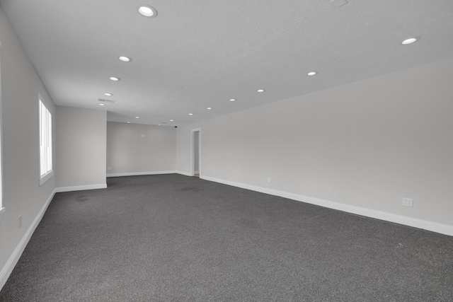 empty room featuring recessed lighting, dark carpet, and baseboards