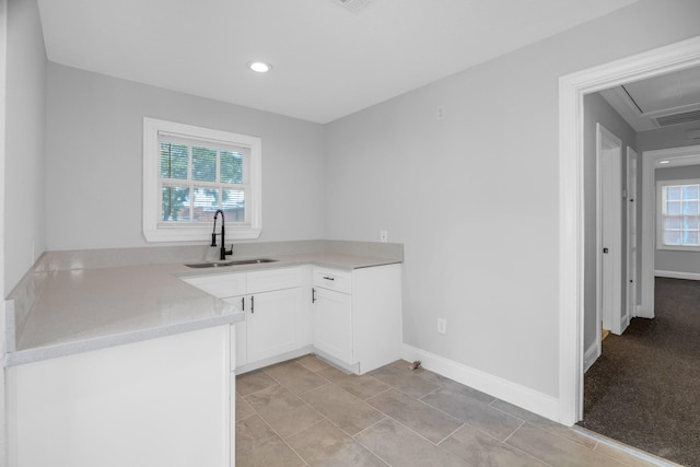 kitchen featuring light countertops, a sink, white cabinetry, and baseboards