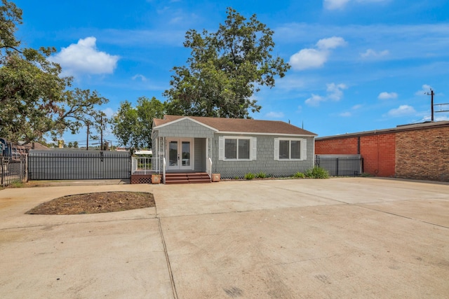 view of front facade featuring fence, concrete driveway, and french doors