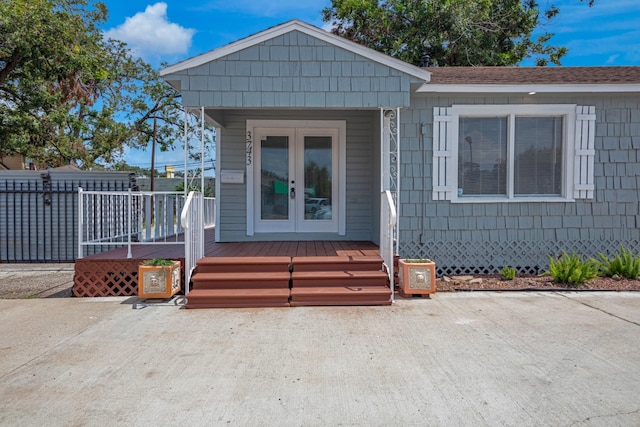 view of front facade featuring a wooden deck, fence, and french doors