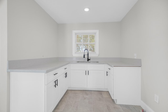 kitchen with light tile patterned floors, light countertops, white cabinetry, a sink, and recessed lighting